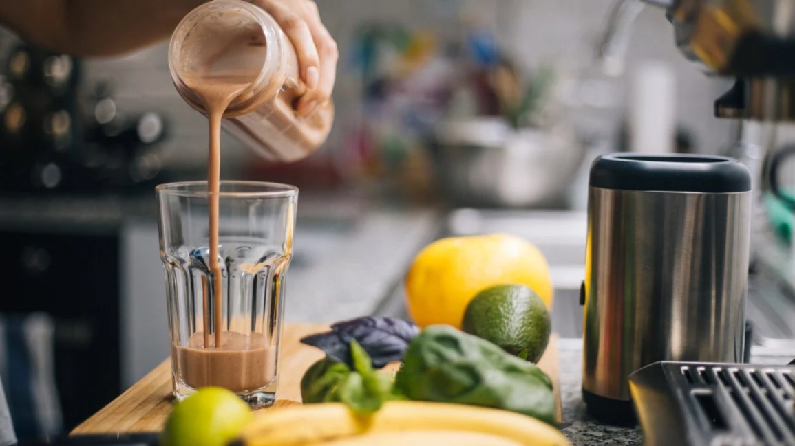 pouring protein shake from blender into a glass